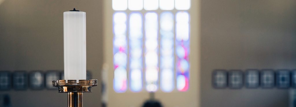 Altar candle with stained glass window in background